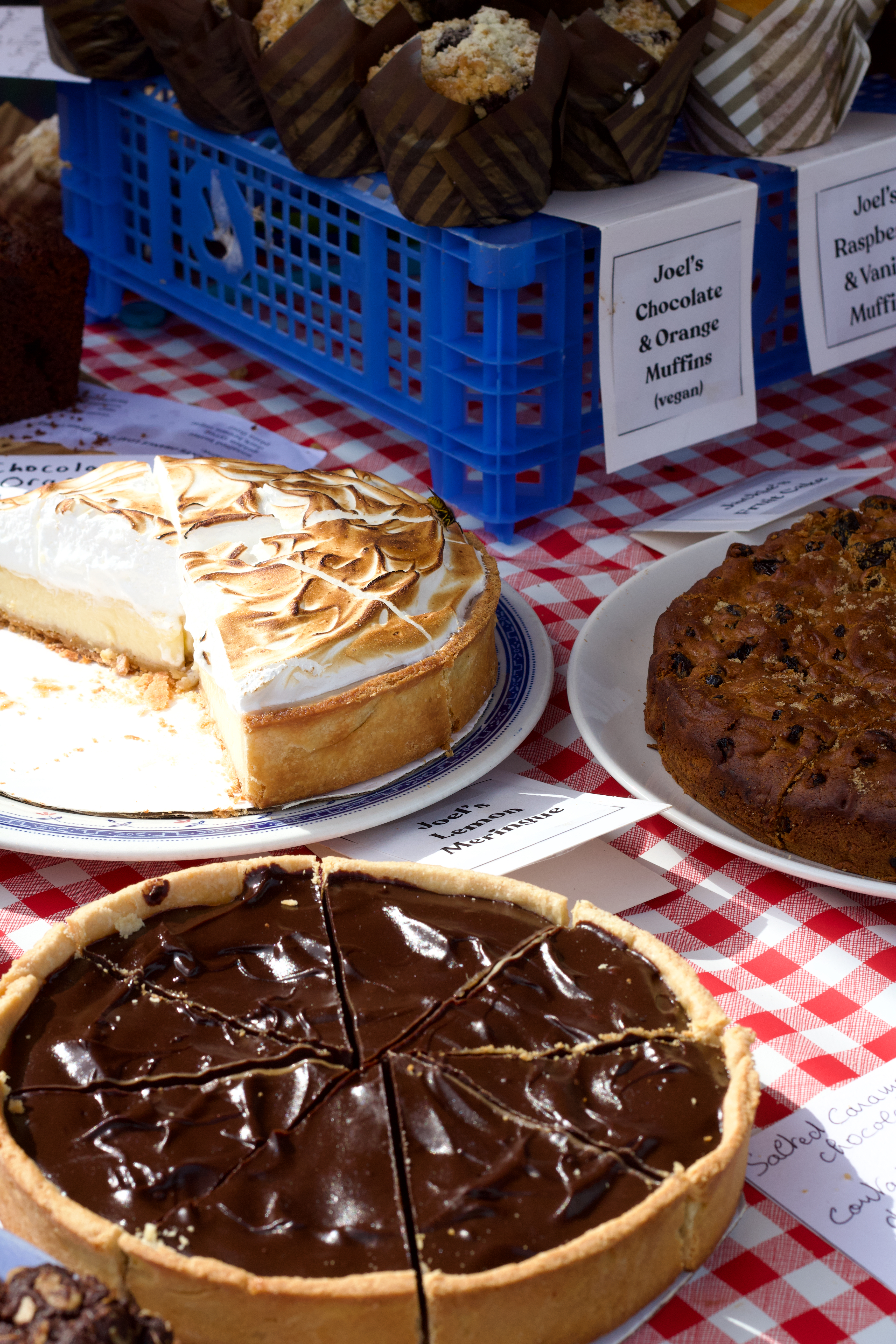 Bakes on a market stall — lemon meringue, chocolate tart and muffins