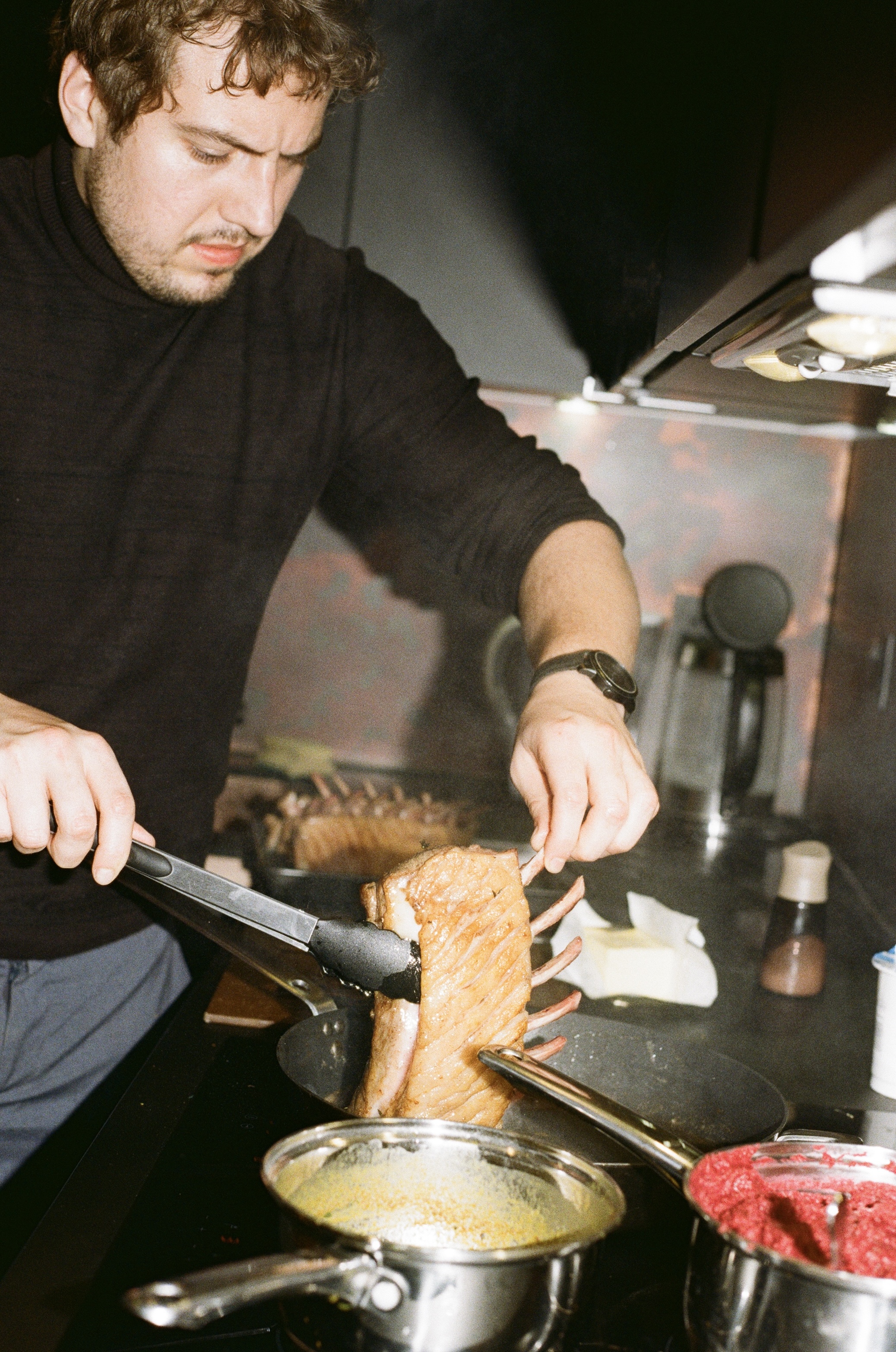 Chef searing a rack of pork in a kitchen, shot on film