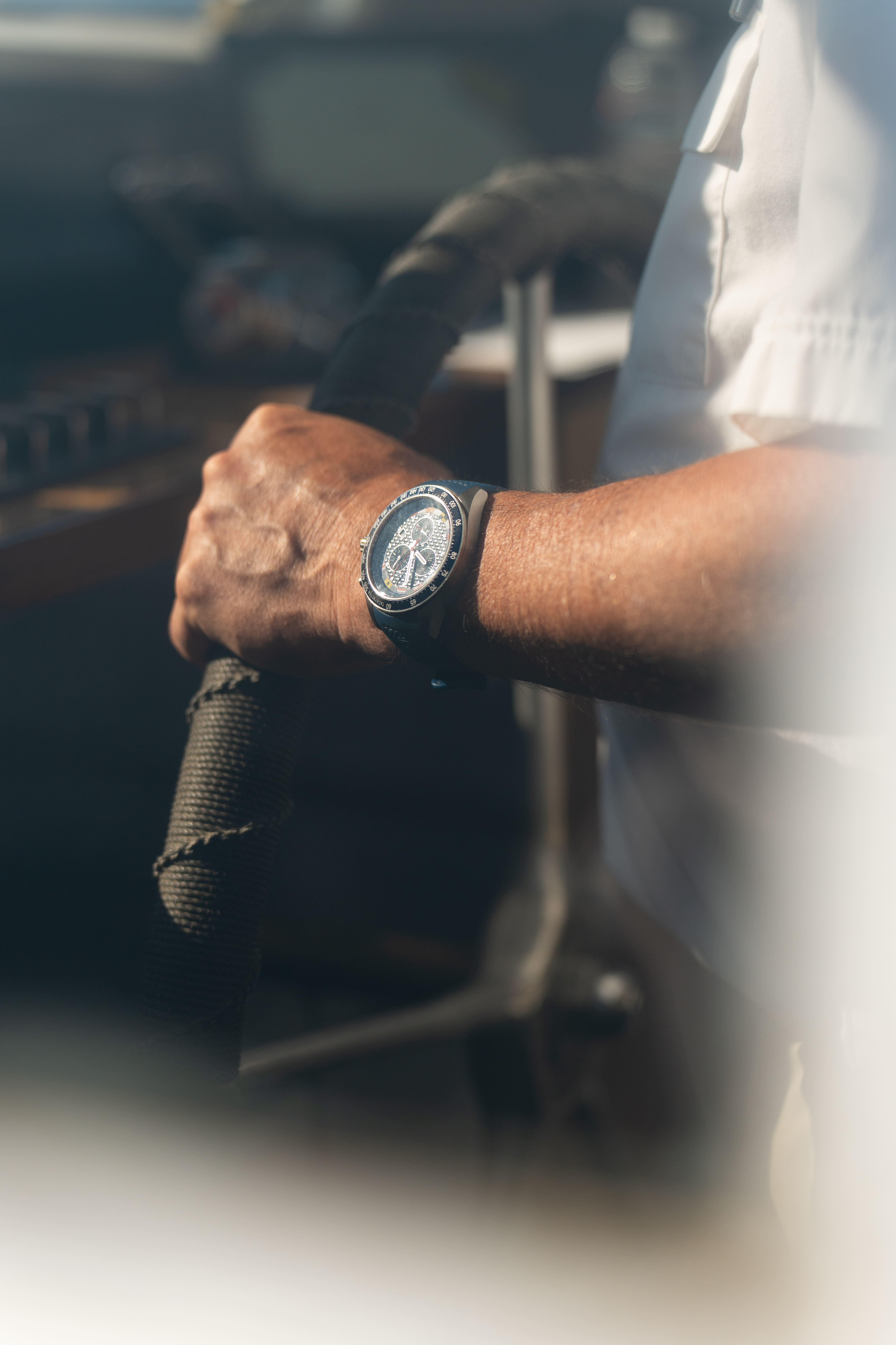 Hand at the helm of a boat, watch in the afternoon sun